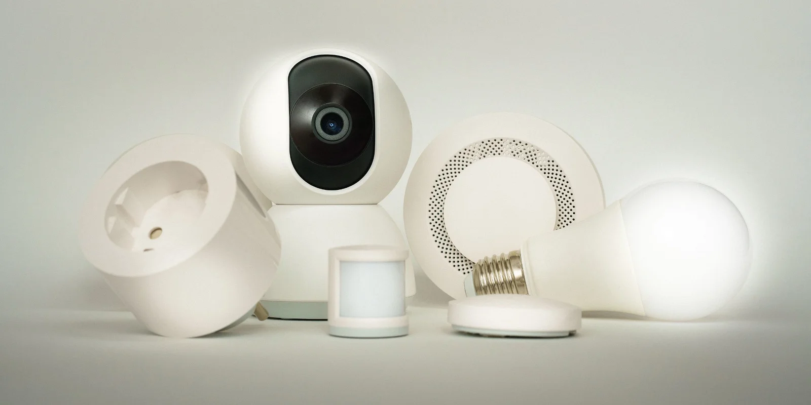 A collection of smart home accessories including a camera, plug, sensors and light bulb